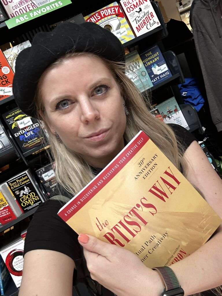 Natalie Forslind holding the book: The Artist's Way by Julia Cameron. 
